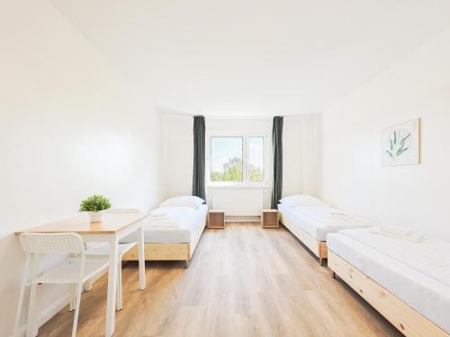 a white room with a table and white beds at Tolstov Apartments - Monteurwohnungen - 2 Schlafzimmer - Küche - Balkon - Waschmaschine in Heiligenhaus