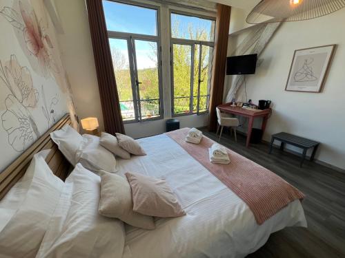 a bedroom with a large bed with pillows and a desk at Logis Hôtel Auberge de Cartassac in Sarrazac