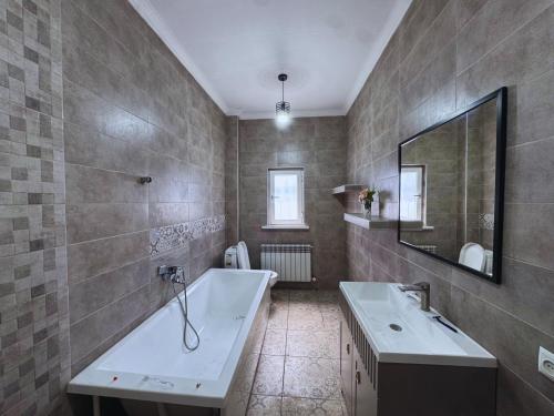 a bathroom with a tub and a sink and a mirror at Meridian Hostel in Almaty