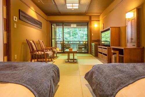 a bedroom with two beds and a living room at Shionoyu Onsen Rengetsu in Nasushiobara