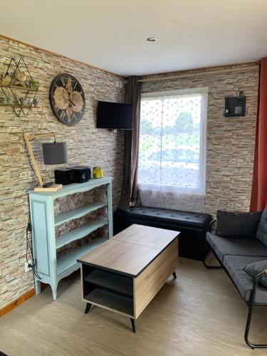 a living room with a couch and a clock on a brick wall at Gîte du Phare in Lanquais