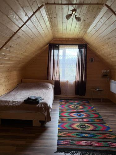 a bedroom with a bed and a rug on the floor at Трофейна хатина in Krivopolʼye