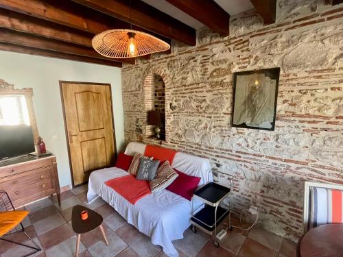 a living room with a couch and a stone wall at Manoir La Bordeneuve in Villeneuve-sur-Lot