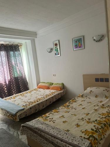two beds sitting in a bedroom with a window at S1 a louer in Dar el Saïd