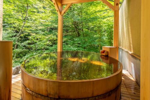a hot tub on a deck with a view of the woods at Shionoyu Onsen Rengetsu in Nasushiobara