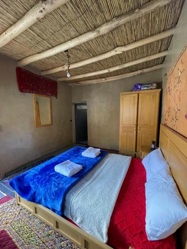 a bedroom with a large bed with a blue comforter at Auberge Restaurant Oumidou in Agoudal