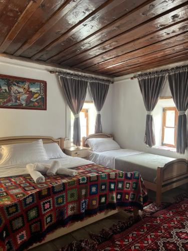 two beds in a bedroom with a wooden ceiling at Guesthouse Kujtimi in Theth