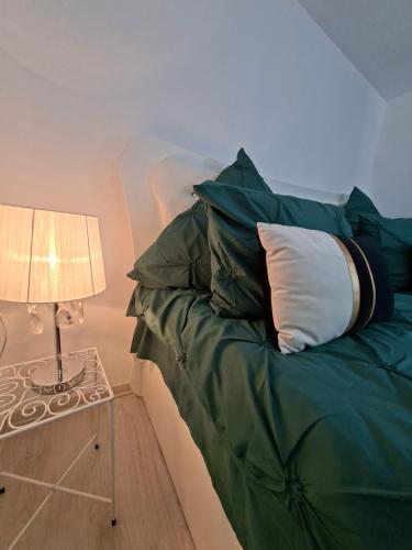a green bed with a white pillow and a lamp at Casuța Râului in Zărneşti