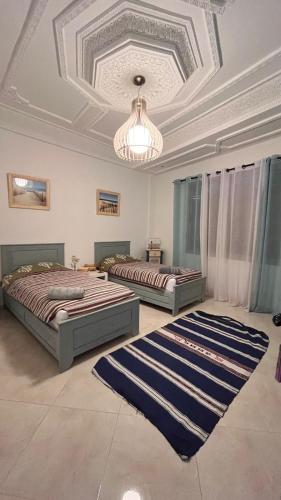 two beds in a room with a ceiling at Villa Michel in Tamraght Ouzdar