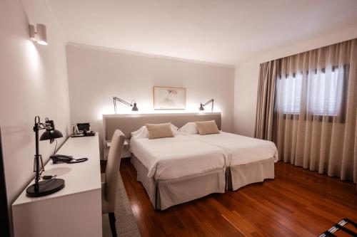 a white bedroom with a white bed and a desk at Hotel Escuela Santa Brígida in Santa Brígida