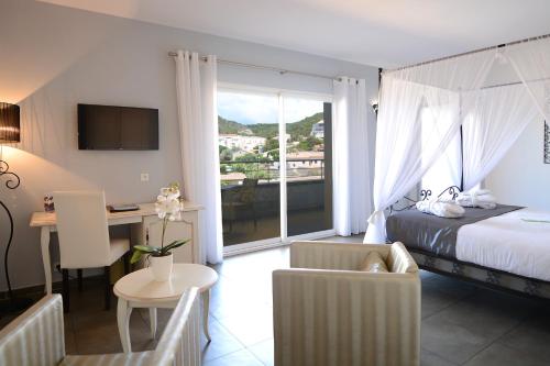 a hotel room with a bed and a desk and a balcony at Hôtel A Madonetta in Bonifacio