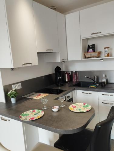 a kitchen with two plates and glasses on a counter at studio moderne les pieds dans l'eau in Larmor-Baden