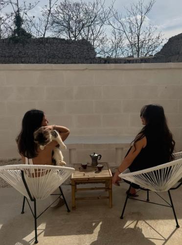 two women sitting in chairs with a dog on a table at Ma'Bella - MASSERIA PICCOLA by Rentbeat in Cisternino