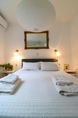 a bedroom with a large white bed with a mirror at Guesthouse Thomas in Vátos