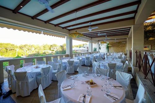 a banquet hall with white tables and white chairs at Hotiday Torre Santo Stefano Resort in Otranto