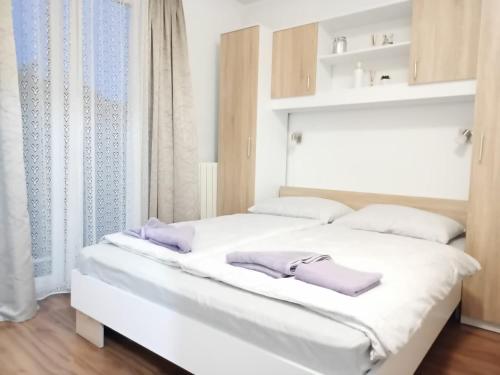 a white bed with two purple slippers on it at Villa Meja in Hreljin