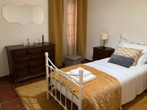 a bedroom with a white bed and a dresser at Alojamentos Vila Alpalhão in Alpalhão