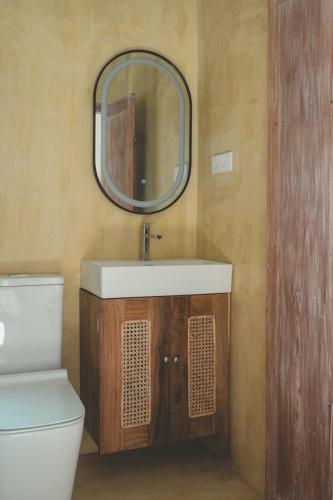 a bathroom with a sink and a mirror and a toilet at Casa Mariposa in Ahangama