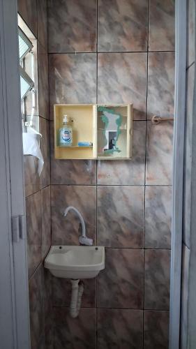 a bathroom with a sink on a tiled wall at Kitnet quarto e cozinha ha 3min da Unifesp in São Paulo