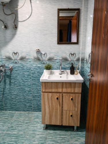 a bathroom with a sink and a shower with birds on the wall at Harshil Pinewood Homestay in Harsil