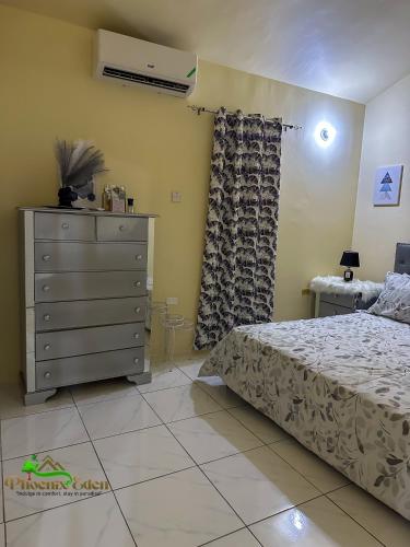 a bedroom with a bed and a dresser at Phoenix Eden in Portmore