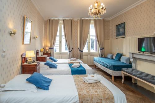 a hotel room with three beds and a tv at Hôtel Restaurant Continental in Évian-les-Bains