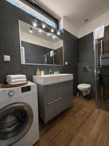 a bathroom with a washing machine and a sink at Apartamenty Przy Latarni Kropla Bałtyku in Darlowko