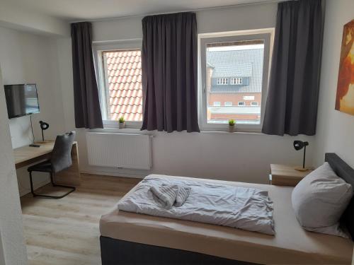 a bedroom with a bed and a desk and two windows at Altes Gesellenhaus in Dinklage