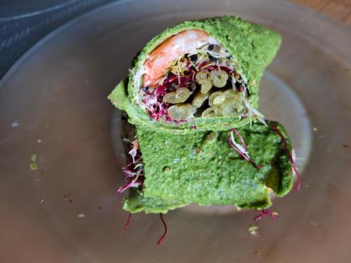 a sandwich on a plate with green sauce and vegetables at Chambre double avec balcon in Sérignan