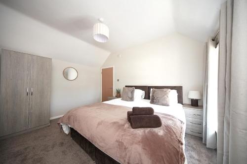a white bedroom with a large bed with a brown blanket at Bedford Retreat in Bedford