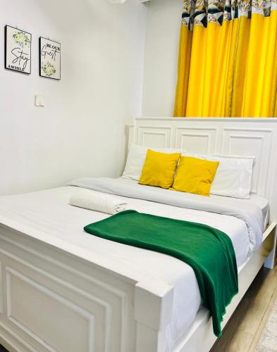a large white bed with yellow and green pillows at Airport Studio Gym pool fast WIFI Ideal for digital nomads Syokimau in Syokimau