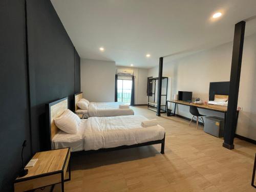 a hotel room with two beds and a desk at Sinai Hotel in Rayong