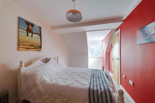 a bedroom with a white bed and a red wall at Wonderful Worthing Beach Walk Flat in Worthing