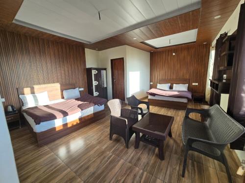 a hotel room with two beds and a table and chairs at HKS Orchards Stay in Kanatal
