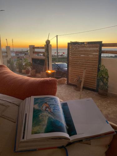 an open book on a couch with a sunset in the background at Slow Life in Imsouane