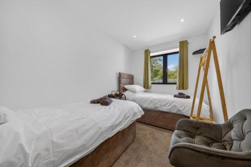 a bedroom with two beds and a chair at Luxury Norfolk Barn for 12 with Hot Tub , Games Room & EV Car Port in Lenwade