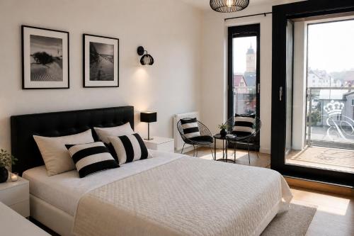 a bedroom with a large bed and a balcony at Apartamenty Przy Latarni Kropla Bałtyku in Darlowko