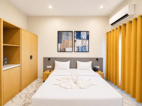 a bedroom with a white bed with yellow curtains at Ixoras Hotel Lemba in Kinshasa
