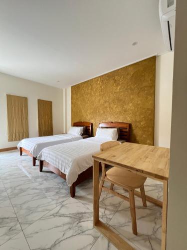 a room with two beds and a table in it at Wiang Kham Resort in Ban Na Phra That