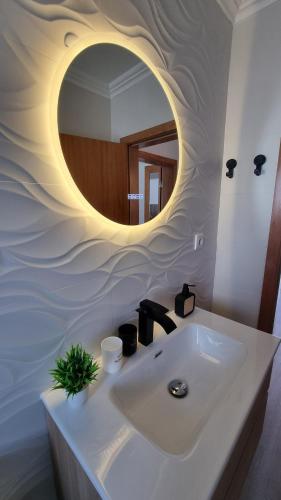 a bathroom with a sink with a circular mirror at Mar & Monte in Angra do Heroísmo