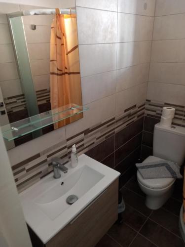 a bathroom with a sink and a toilet and a mirror at Apartment PAPAS in Mastihari