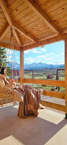 a woman sitting in a hammock on a porch at Green Top Durmitor in Žabljak