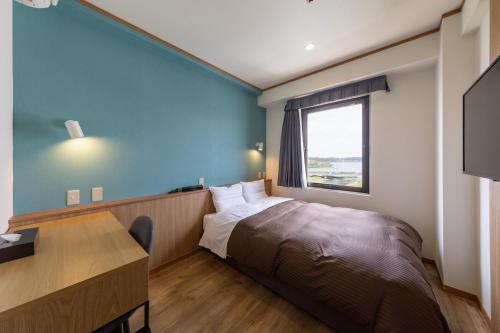 a bedroom with a bed and a desk and a window at Mito Hotel Season in Mito