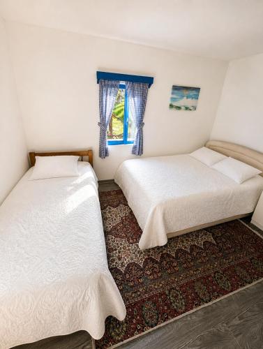 two beds in a room with a window at Etno kuća Radonjić - Family Retreat & Spa in Guča