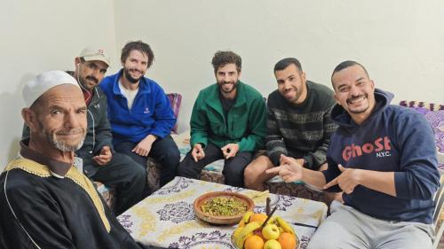 a group of men sitting around a table with a bowl of food at اميزميز in Amizmiz