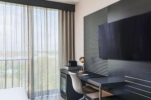 a hotel room with a desk and a large television at AC Hotel by Marriott Georgetown Guyana in Georgetown