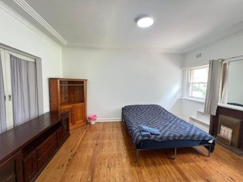 a living room with a bed and a wooden floor at Room 53 in Sydney