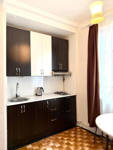 a kitchen with black cabinets and a sink and a table at Nice Apartment in the City Center in Yerevan