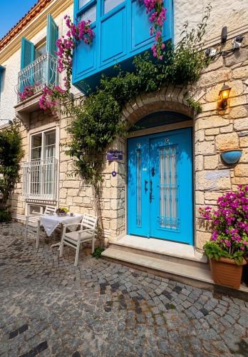 a blue door on a building with a table at Mavi Konak Alaçatı in Alaçatı