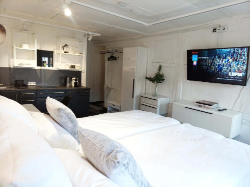 a bedroom with a white bed and a television on the wall at NOX HOTEL - Digital-Check-In - No Reception - nahe Bretten & Karlsruhe - 5 Future in Wössingen